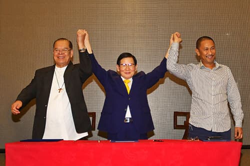 Drei Unterzeichner heben nach der Unterzeichnung des Mindanao-Friedensabkommens gemeinsam die Hände.